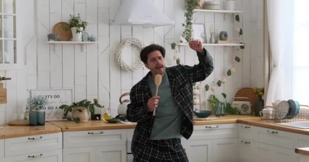 男人一边在厨房里拿着铲子一边跳舞唱歌 玩得很开心 — 图库视频影像