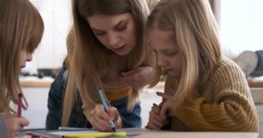 Kafkasyalı genç annenin evde resimlerini çizerken gülümseyen ve yardımcı olan kızlarının yavaş çekimleri.