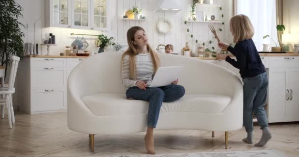 Irritated Businesswoman Sitting Sofa Working Laptop While Playful Daughters Banging — Stock Video