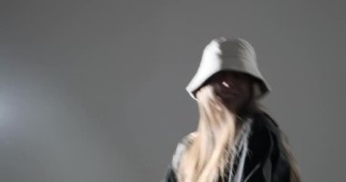 Spor sutyenli aktif bir kadın ve hip hop tarzında düğmesiz tişört dans ediyor.