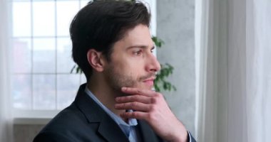 Ofis penceresinden dışarı bakan düşünceli bir işadamı.