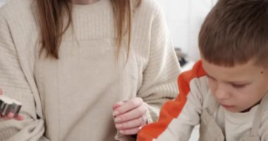 Çocuklu anne mutfak tezgahında kesiciyle zencefilli kurabiye yapıyor.