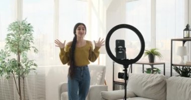 Canlı Hintli vlogger tutkuyla evdeki hikayeleri paylaşıyor. Günlük kıyafetlerle, halka ışığıyla bir telefonun önünde duruyor, sosyal medya için büyüleyici videolar çekiyor ya da canlı yayın sunuyor..