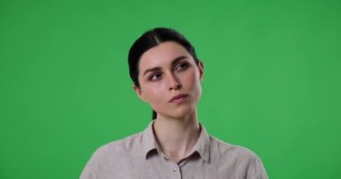Beyaz kadın yeşil ekran arka planında duruyor, düşünüyor ve bir fikir arıyor. Sonunda aklına bir fikir gelene kadar etrafına bakınır ve dahice bir çözüm olduğunu göstererek parmağını kaldırır..