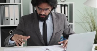 Yavaş çekim, ofiste oturan Hintli bir işadamı belgeleri inceliyor. Daha büyük sorunlara yol açabilecek bir hata fark etti. Ellerini başının üstüne koyar, baş ağrısı hisseder..