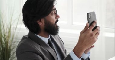 Yavaş çekimde, Hintli bir CEO ofisinde oturup telefonuyla bir video konferans görüşmesi yapıyor. Keyfi yerindeymiş gibi görünüyor, meslektaşlarıyla hareketli bir şekilde iş stratejilerini tartışıyor..