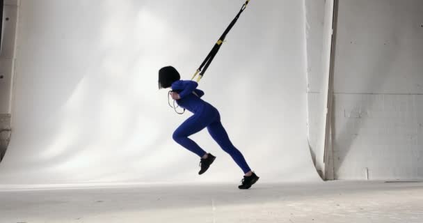 一个自信的白人女人穿着蓝色运动服和运动鞋 手紧紧抓住健身带 向后冲刺 侧面看 — 图库视频影像
