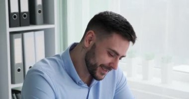 Beyaz, sakallı ve iş kıyafeti giymiş bir işadamı ofisteki masasında keyfi yerinde oturuyor. Büyük bir gülümsemeyle kameraya doğru dönüyor..