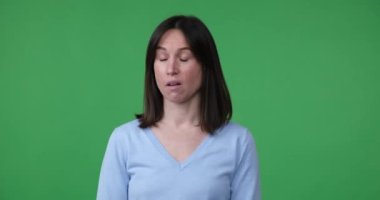 Yeşil ekranda duran beyaz bir kadın hayal kırıklığına uğramış ve hayal kırıklığına uğramış görünüyor. Gördüğü ya da duyduğu şeyden duyduğu memnuniyetsizliği belirterek inançsızlıkla yüz yüze geliyor..