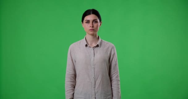 Mujer Aspecto Serio Pone Pie Contra Una Pantalla Verde Muestra — Vídeo de stock