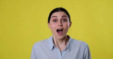 Beyaz bir kadının portresi sarı arka planda duruyor, doğrudan kameraya bakıyor ve aniden hayret verici bir şey görüyor, yüzünde kocaman bir gülümsemeyle 