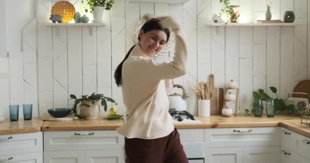 快乐的白人女人快乐地在厨房里跳舞 她描绘了自己灿烂的笑容 充满活力的舞步 以及散发出来的传染性的积极向上的能量 — 图库视频影像