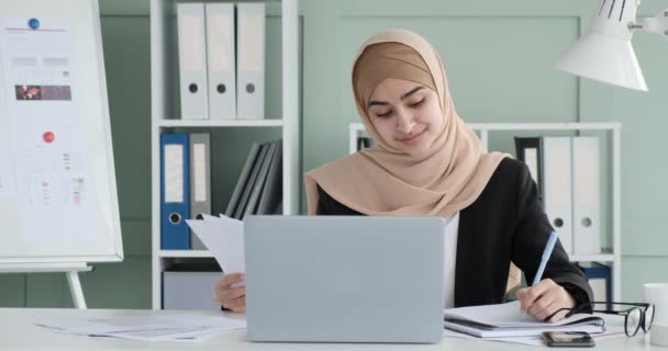 Młoda Arabska Bizneswoman Ozdobiona Hidżabem Siedząc Przy Biurku Promieniuje Entuzjazmem — Wideo stockowe