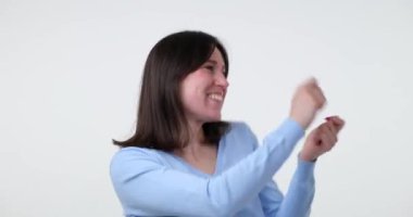 Neşeli beyaz bir kadın beyaz arka planda tasasız dans eder. Hareketleri hızlı, cüretkar ve canlıdır. Bulaşıcı enerjisi ve iyimser ruhu kesinlikle her ruh halini düzeltir..