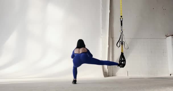파란색 스포츠 슈트를 코카서스 여성은 루프에 다리를 웅크리고 비디오는 운동에 — 비디오