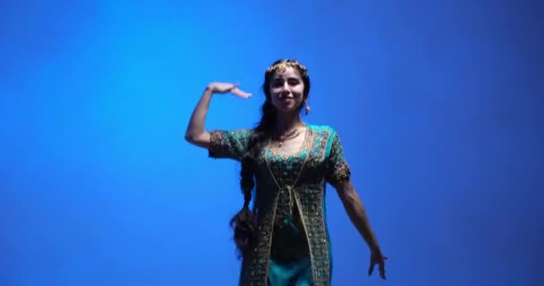 カラフルなセーブと複雑なジュエリーを身に着けている才能のあるインドの若いダンサーをフィーチャーしたインドのダンスパフォーマンス スタジオは青と煙の背景で撮影 — ストック動画
