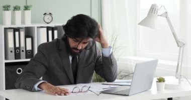 Ofisindeki masasında oturan Hintli işadamı masasındaki bazı kağıtları karıştırıyor. Son teslim tarihi yaklaştıkça, işi tamamlamakta zorlanıyor ve baş ağrısı çekiyor gibi görünüyor.