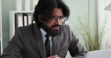 Hintli bir iş adamı ofisinde dizüstü bilgisayarı üzerinde çalışırken, onu hemen sinirlendiren ve sinirlendiren bir şey görür. Yüksek sesle bağırıyor.