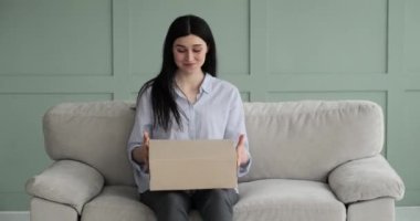 Bir paket alıp açan neşeli beyaz bir kadının portresi. Kanepede otururken heyecanla kutuyu açar ve içinde ne olduğunu öğrendiğinde yüzü heyecanla ışıldar..