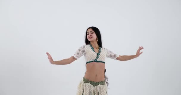 白と緑のサリで伝統的なインド舞踊を披露しながら この若いインド人女性は優雅さと流動性で動き 彼女の宝石類は彼女のパフォーマンスに美しさと優雅さの余分な層を追加します — ストック動画