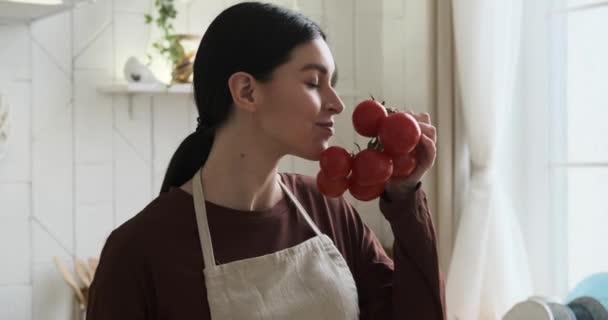 厨房里的白人女人 在烹饪探险中散发着积极向上的气息 她满怀期待地采摘丰满的西红柿 品尝着它们的香味 在木板上切碎西红柿 — 图库视频影像