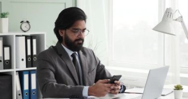 Gözlüklü, takım elbiseli ve kravatlı Hintli bir işadamı masasında oturmuş telefonuna yazı yazıyor ve arkadaşlarıyla sohbet ediyor. Meşgul ve telefonuna odaklanmış, konuşmanın tadını çıkarıyordu.