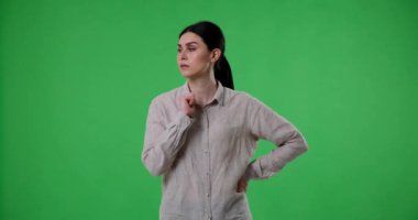 Kafası karışmış Kafkas kökenli bir kadın yeşil perde arkasında duruyor ve karmaşık bir duruma çözüm arıyor. Şaşkın şaşkın bakıyor, başını tutuyor ve endişeyle etrafa bakıyor..