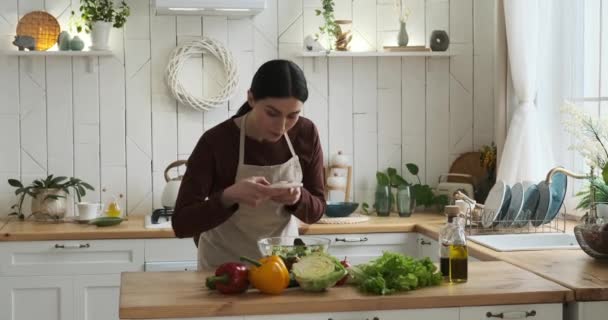 聪明的白人女人 站在厨房里 捕捉精美色拉的精华 她巧妙地拍摄了烹饪杰作 准备与在线社区分享美食的乐趣 — 图库视频影像