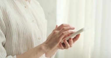 Bir kadının eli, telefonunda ustalıkla kaydırma, kaydırma ve tarama yaparken yakındır. Parmakları ekranda zahmetsizce süzülüyor ve mobil teknolojideki ustalığını ortaya koyuyor..