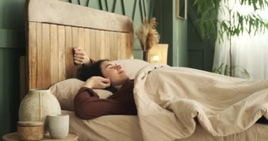 Kafkasyalı bir kadın sabah rahat pijamalarıyla uyanır uyanmaz. Yatağının yumuşaklığında rahatça uzanıyor ve lüksünü sergiliyor. Rahatlama ve sükunet hissi yayıyor..