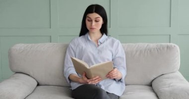 Kanepede oturan beyaz bir kadının portresi, dikkatle kitap okuyor ve yüzünde ciddi bir ifadeyle sayfaları çeviriyor. Kendini tamamen okumaya verdi..