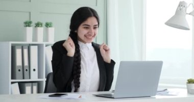 Hintli iş kadını kendisini heyecanlandıran harika haberler alıyor. Yüzünde mutlu bir ifadeyle ellerini muzaffer bir şekilde havaya kaldırır ve haykırır: