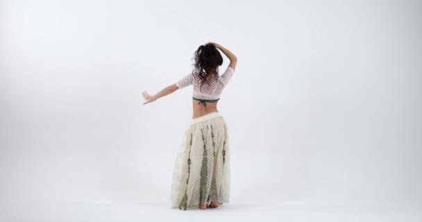 インドの若い女性のエネルギーは 伝統的なインドのジュエリーで飾られた白いサリーで活気のあるインドのダンスを踊るように伝染しています 彼女のパフォーマンスは色 表現でいっぱいです — ストック動画