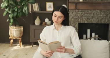 Beyaz kadın oturma odasında rahat bir kanepeye oturur. Huzurlu bir ifade ve güvence duygusuyla, kendini büyüleyici bir kitaba daldırıyor, sessiz bir düşüncenin tadını çıkarıyor..