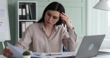 Ofiste çalışan ve önünde kağıtlar olan bir kadın. Kağıdı dikkatlice inceliyor ve bir kalemle notlar alıyor. Bu sırada da bir hesap makinesiyle bütçe hesaplaması yapıyor..