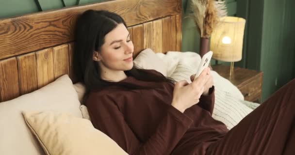 Wesoła Biała Kobieta Siedząca Łóżku Wygodnie Ubrana Piżamę Jest Pochłonięta — Wideo stockowe