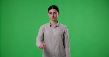 Beyaz kadın reddederek parmağını sallayarak onaylamadığını ifade ediyor. Vücut dili ve hareketleri açık bir şekilde muhalefet ve isteksizlik mesajı iletiyor..