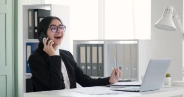 Ofis masasında oturan neşeli Hintli kadın molada arkadaşlarıyla canlı bir telefon görüşmesi yapıyor. Parlak bir gülümsemeyle, zahmetsizce işi ve kişisel bağlantıları dengeliyor..