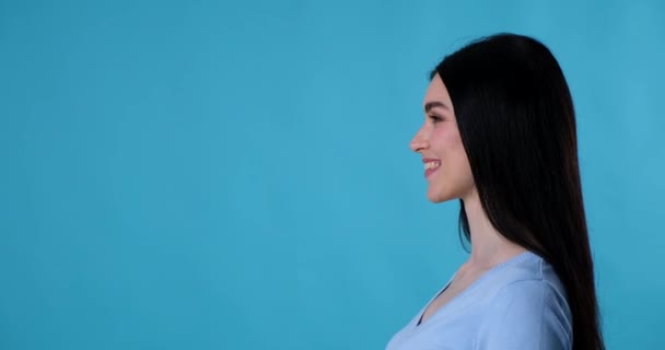 Beyaz Kadın Mavi Arka Planda Profilde Duruyor Gülümsüyor Işaret Parmağıyla — Stok video