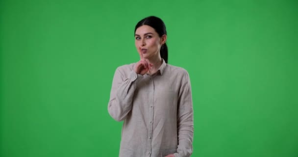 Cheerful Caucasian Woman Stands Green Screen Background Shows Hush Gesture — Stock Video
