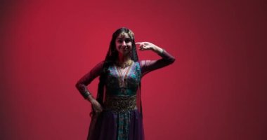 Mavi, mor ve yeşil renkli sari giymiş genç bir kadının Hint dansı. Zarif hareketleri ve canlı yüz ifadeleri performansının gerçekliğini artırıyor..