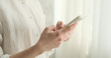 Akıllı telefonunda ustalıkla yazı yazan bir kadının el ele tutuşması yakın plan görüntüsü. Ekranda süzülürken parmaklarının karmaşık hareketlerine odaklan, zahmetsizce tıkırdıyor..