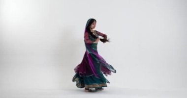 Renkli ve karışık desenli güzel bir sari giymiş genç bir bayanın büyüleyici Hint dansını izleyin. Geleneksel Hint müziğine doğru zarif bir şekilde ilerlerken....