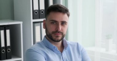 Kafkas kökenli başarılı bir girişimci masasının arkasında oturuyor, kameraya gülümsüyor, azim ve başarı havası yayıyor..