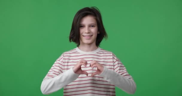 Young Boy Stands Green Screen Background Looks Camera Makes Heart — Stock Video