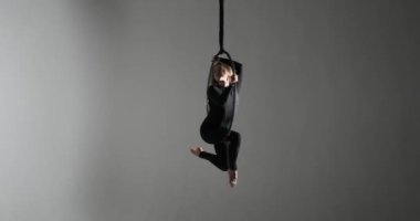 Karanlık bir stüdyonun spot ışıkları altında, hava çemberinde beyaz bir dansçı nefes kesen performansıyla yer çekimine meydan okuyor. Siyah bir tulum giyerek hem güç hem de esneklik sergiliyor..