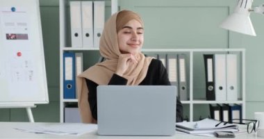 Başörtüsü takmış Arap iş kadını işe dalmış, dizüstü bilgisayarında daktilo yazıyor. Bir anlığına gözünü ekrandan ayırır. Gözleri rüya gibi bir ifadeyle doludur..