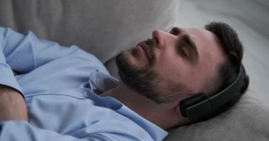 Kafkasyalı bir adam kanepede uzanıyor, kulaklık takıyor ve müzikten hoşlanıyor. Görünüşte rahat ve sakin, müziğin onu sakinleştirmesine izin veriyor. Uzun bir günün ardından rahatlama, rahatlama ve gevşeme..