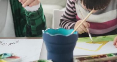 İki beyaz çocuk, bir oğlan ve bir kız, rahat evlerinde yerde oturuyorlar. Ellerinde boya fırçaları ve renkler ile, çok güzel bir sanat eserinde işbirliği yapıyorlar, mutluluk ve heyecan yayıyorlar..
