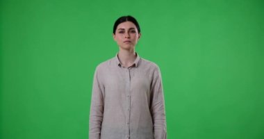 Beyaz bir kadın yeşil ekran arka planında duruyor ve kameraya tarafsız bir ifadeyle bakıyor. Aniden iğrenç bir şey görür ve hafif bir tiksinti duyar..